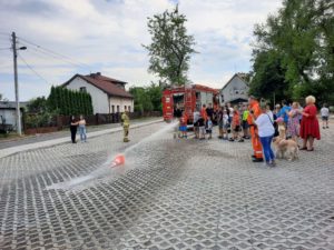 Bezpieczne wakacje - uczestnicy spotkania używają węża strażackiego